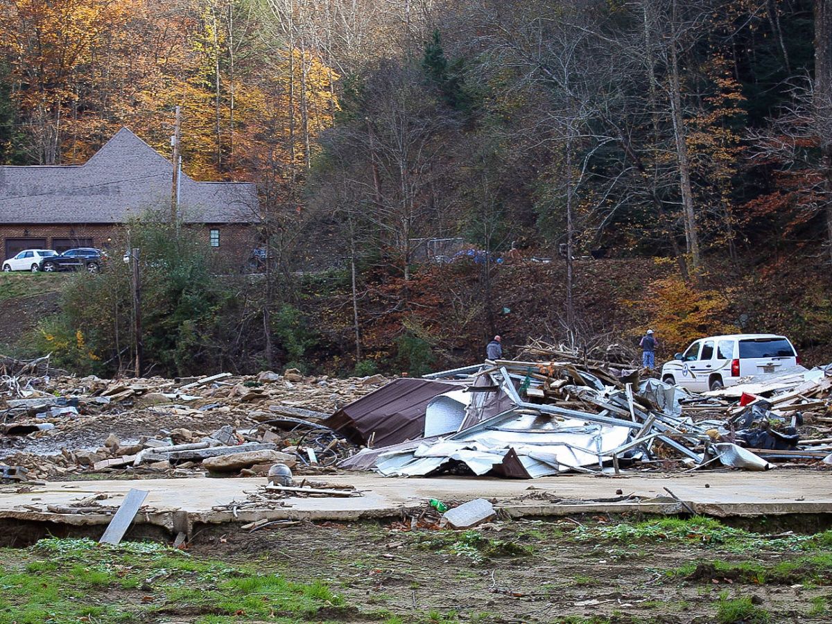 Two men walk through the site of a house leveled by flooding in Hurley