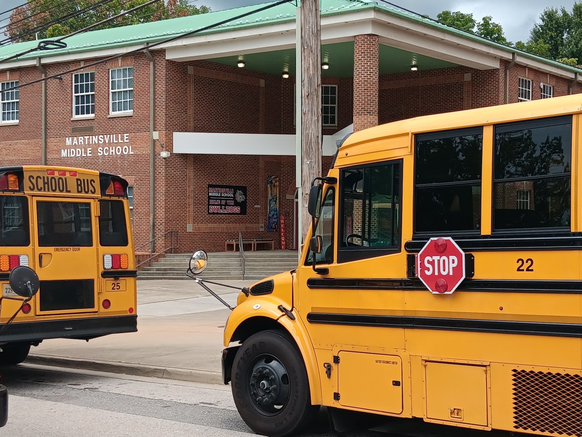 School buses parked outside Martinsville Middle School, a two-story red brick building